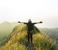 Woman on green mountain top with arms spread wide