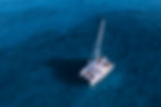 a-serene-aerial-shot-of-a-catamaran-sailing-on-crystal-blue-waters-perfect-for-travel-and-