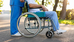 vecteezy_professional-caregiver-assisting-patient-in-wheelchair-outdoors_79597571.jpg