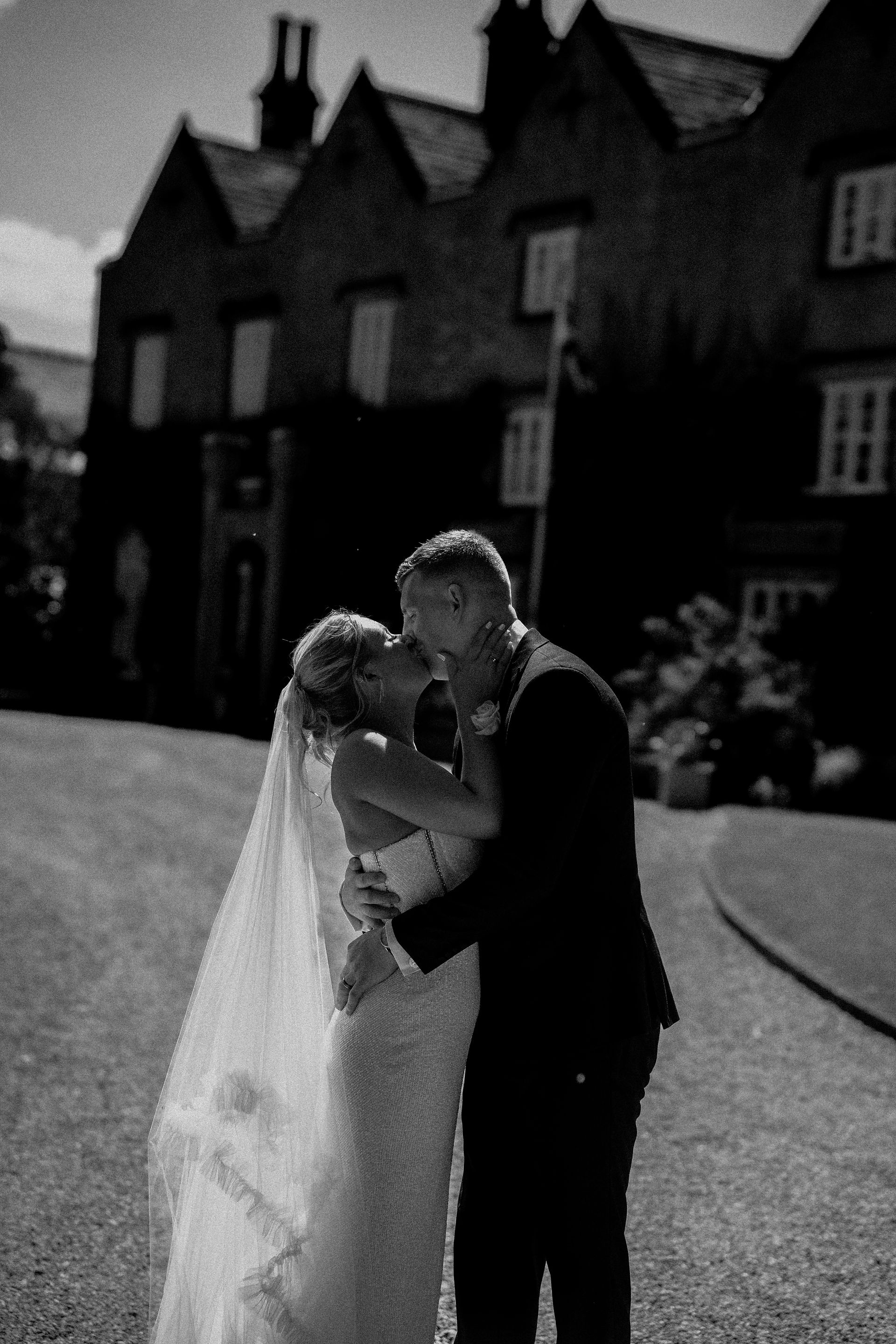 bride and groom having a kiss in front of estate house