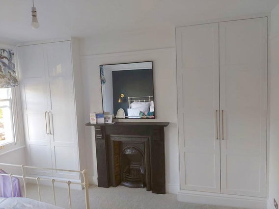 Twin fitted wardrobes featuring Shaker style doors, hanging rails and cupboards by New Heights Carpentry located in Reigate, Surrey. Custom-built for stylish and functional storage.