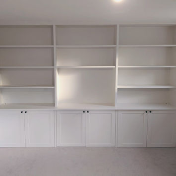 Custom-built alcove units with shelving, cupboards, and pivot sliding doors for a home in Reigate.
