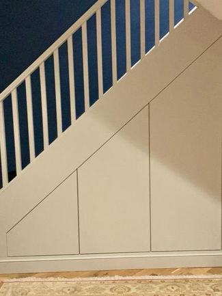 Sleek Bespoke Under-Stairs Storage Solution with Four Large Doors Cabinets and Shelving for a Client in Redhill by New Heights Carpentry.