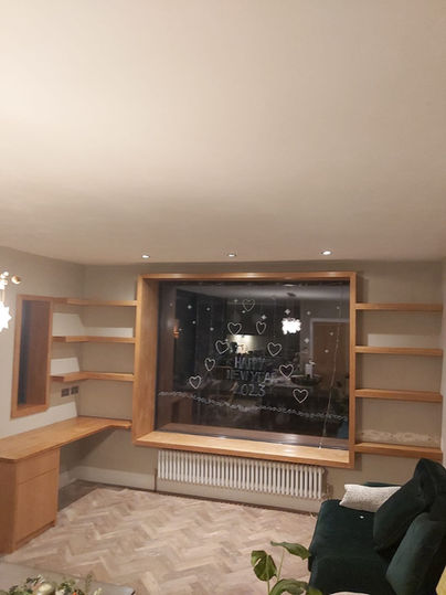  Custom-built wood desk with shelving and a cozy nook seating bench around a window, designed to maximise space and functionality in a stylish, organised setting.