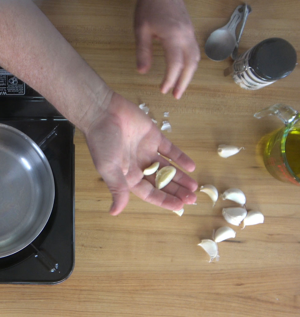 Preparing fresh garlic cloves for a homemade dipping sauce, with olive oil and seasoning ready on the countertop.