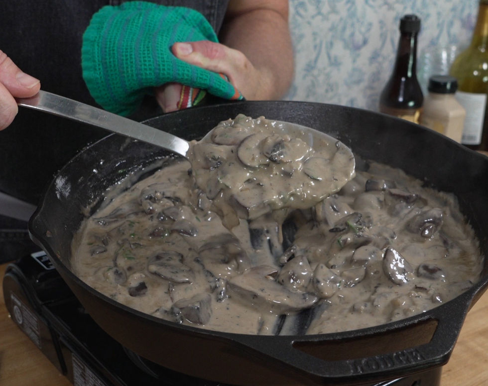 Rich and savory mushroom gravy adorned with baby bella and portabella mushrooms, freshly prepared in a cast-iron skillet.