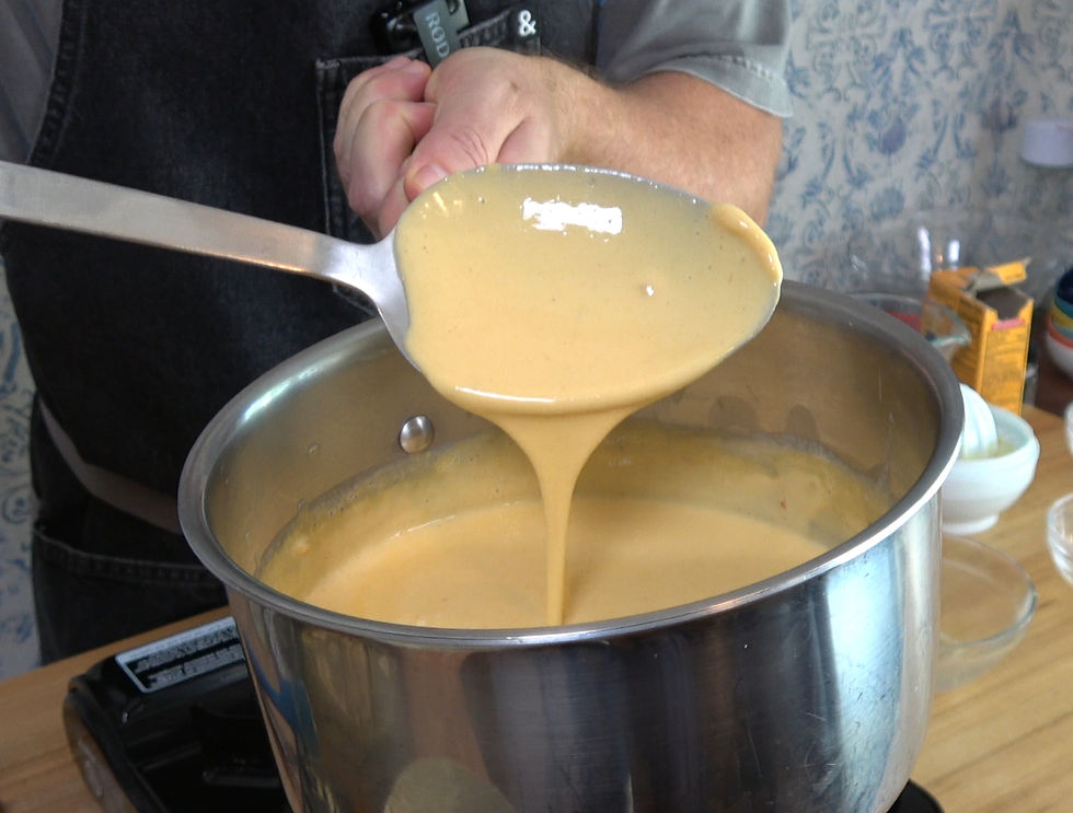 A smooth and creamy nacho cheese sauce is being ladled from a pot, ready to enhance your favorite dishes.