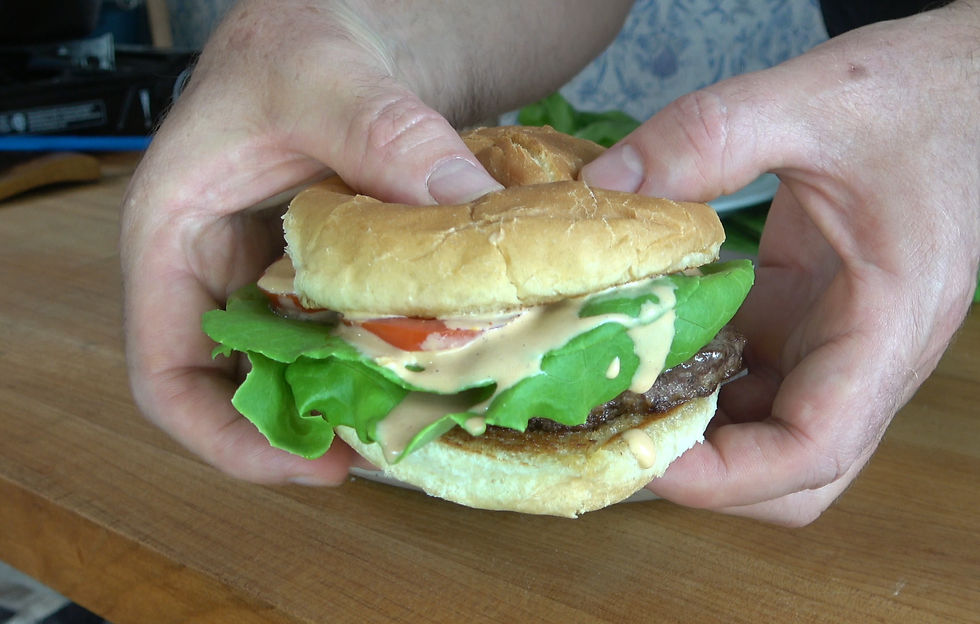 A juicy burger topped with fresh lettuce, tomato, and a generous drizzle of homemade chipotle sauce, ready to savor.