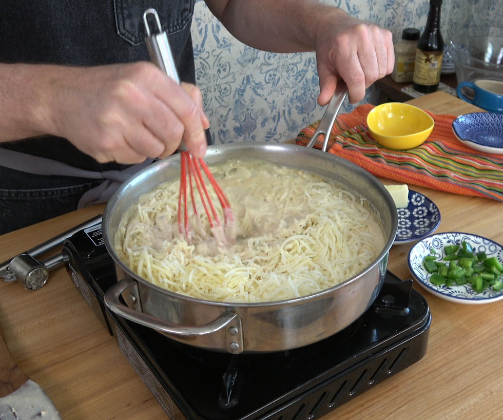 Stirring melted cheese into a creamy sauce for a flavorful jalapeño bacon mac and cheese dish.
