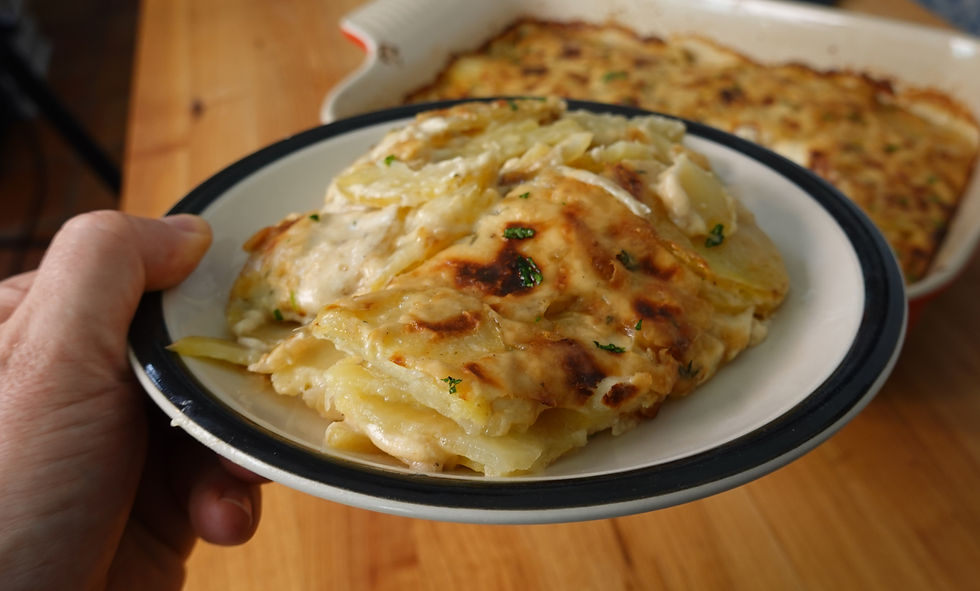 A generous serving of homemade scalloped potatoes recipe, perfectly baked with a golden, cheesy crust and garnished with fresh herbs.