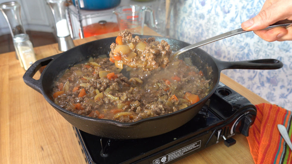 A hearty serving of ground beef and gravy is ready to enjoy, featuring a rich blend of seasoned meat and vegetables in a sizzling skillet.
