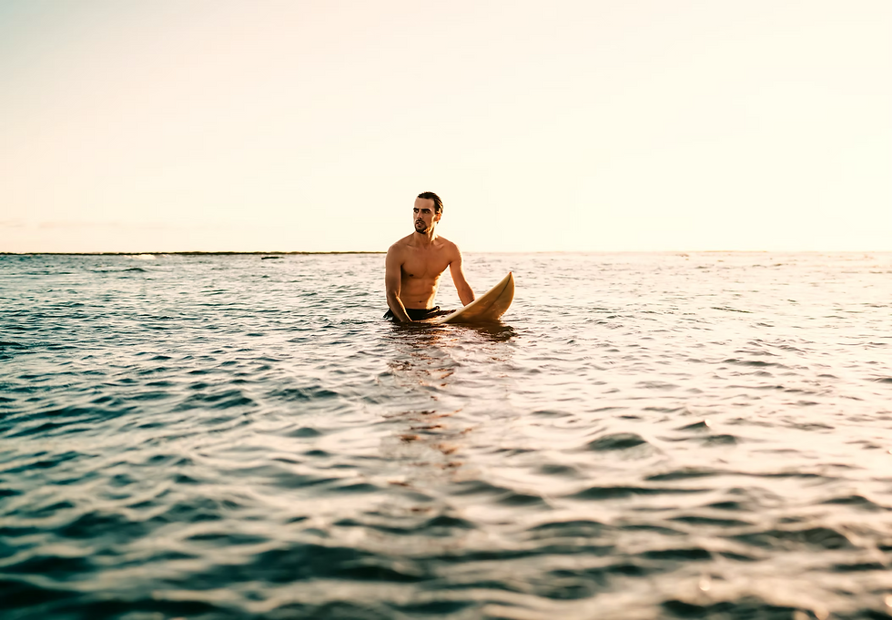 Fit man sitting on surfboard in open ocean at sunset — Leonidas Vitality men's health and peak performance