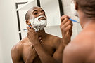 Shirtless man shaving in mirror — Leonidas Vitality hormonal optimization and testosterone therapy