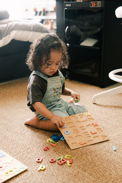 Toddler playing with alphabet toy on carpet floow