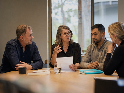 Four professionals discussing organisational governance and reviewing documents around a meeting table.