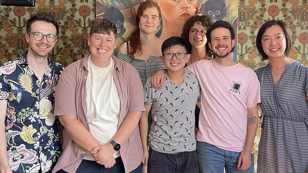 The Trans Health Research team standing in front of a patterned wall and a Frida Kahlo painting.