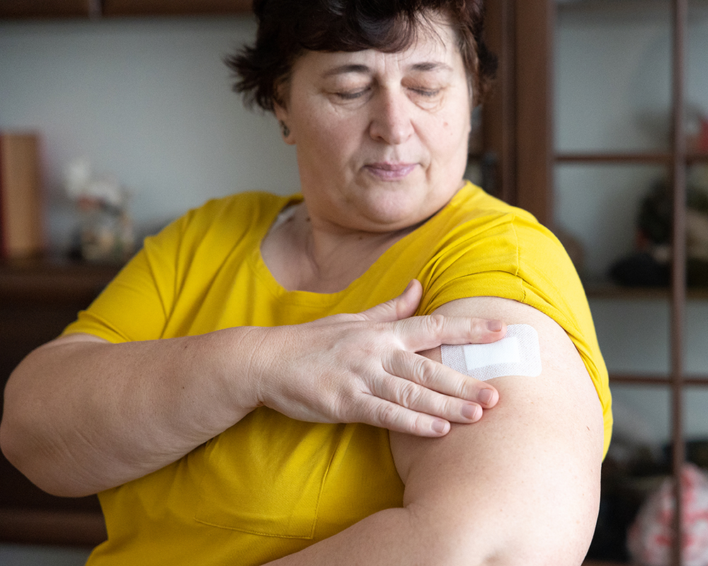 A woman applying an oestrogen patch to her arm