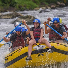 Grupo practicando rafting de clase 2-3 en un río rápido.