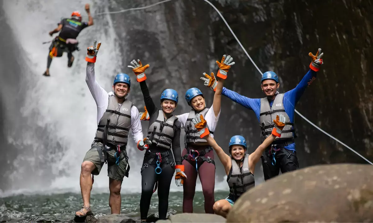 Grupo practicando canyoning frente a una cascada