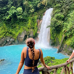 Mujer ante la catarata de Río Celeste en Costa Rica.