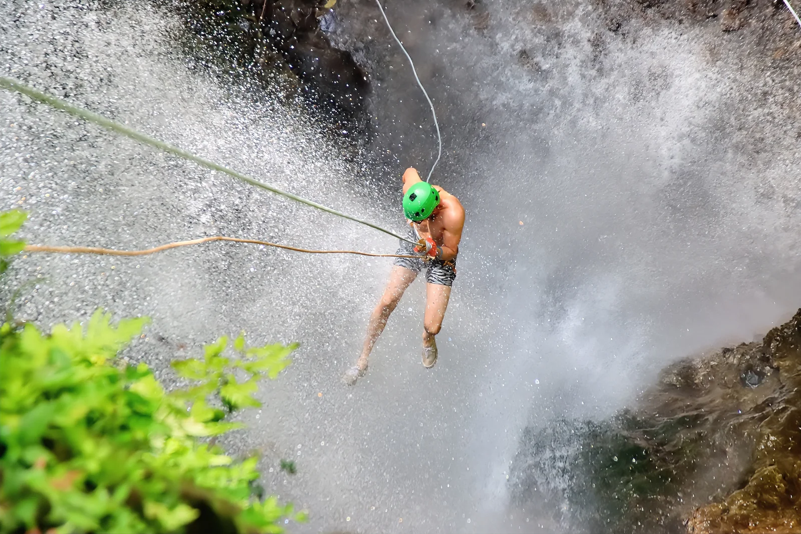 Persona practicando canyoning descendiendo por una cascada.