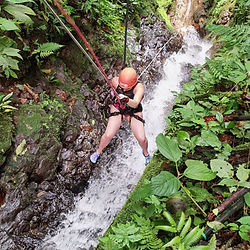 Persona descendiendo en rápel por una cascada en la selva.