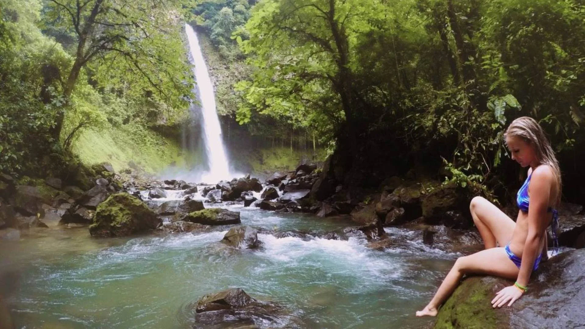 Mujer descansando frente a una cascada en la selva