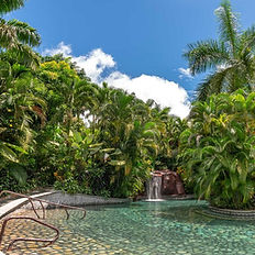 Piscina termal en Baldi Hot Springs con cascada y palmeras