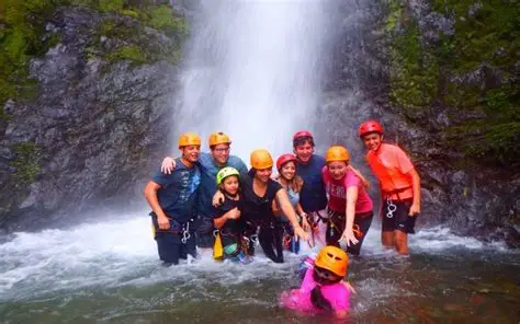 Grupo practicando barranquismo frente a una cascada