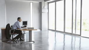 Side view of a senior executive sitting alone at a desk, appearing deep in thought — conveying emotional strain and leadership pressure.