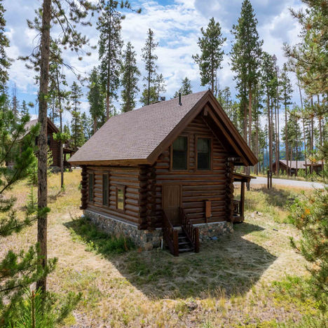Aerial view of rustic log cabin surrounded by pine forest in Colorado mountains – residential real estate photography by Alex Miller