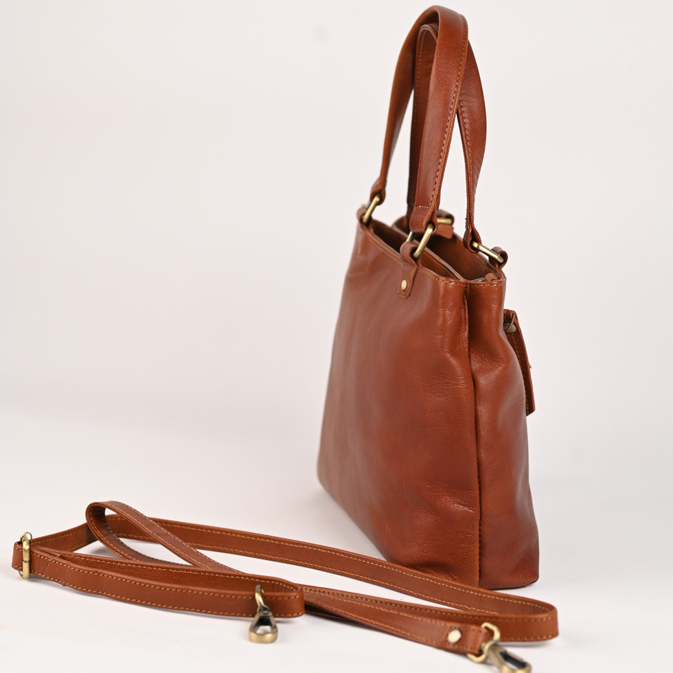 Brown leather handbag with shoulder strap on white background, elegant design.