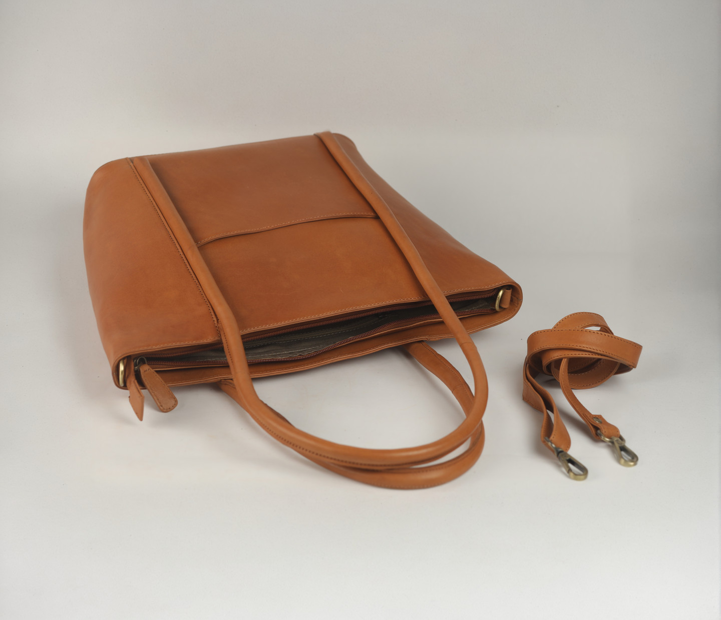 Brown leather handbag with straps and detached shoulder strap on white background.