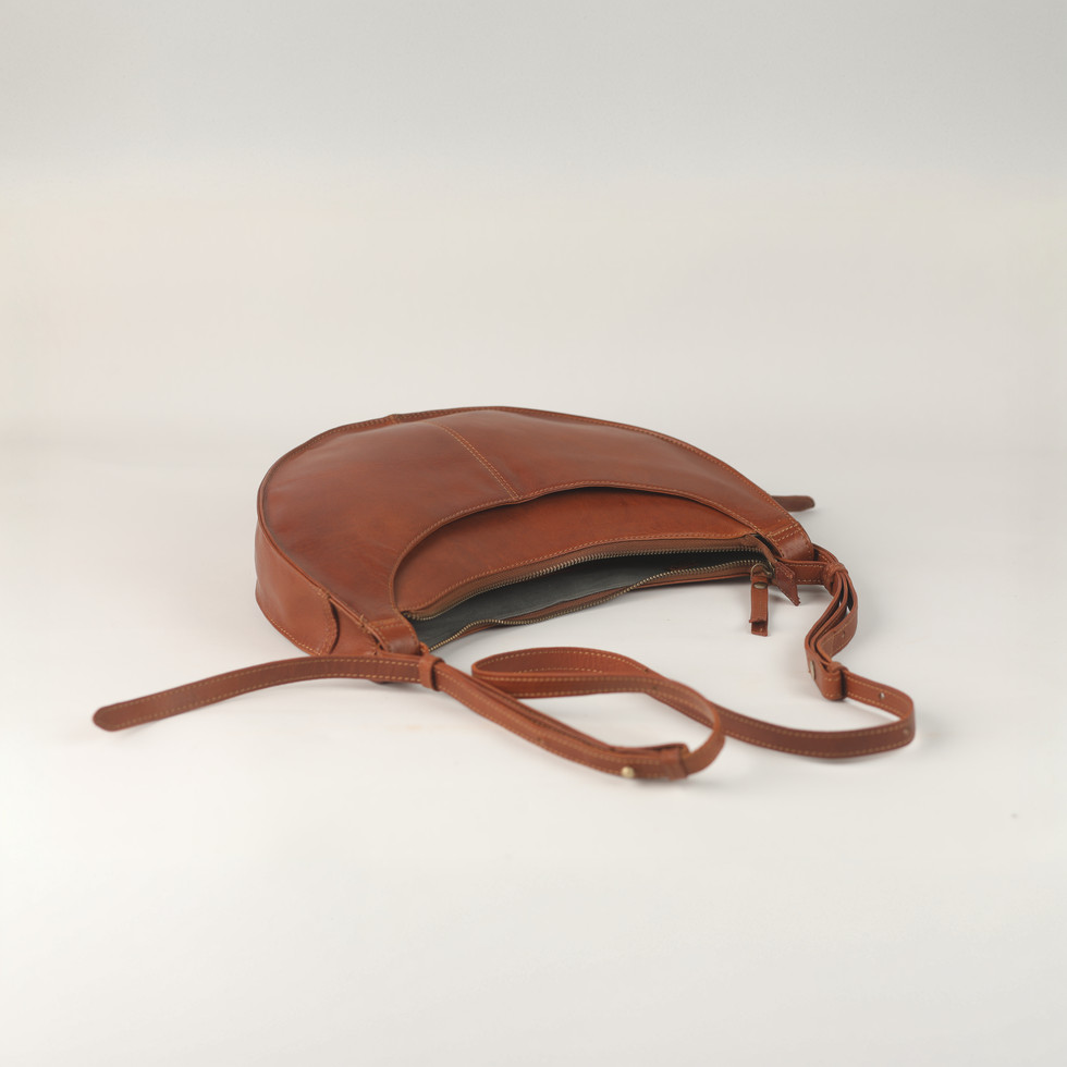 Brown leather bag with strap on white background. Feather Touch Impex Pvt. Ltd.