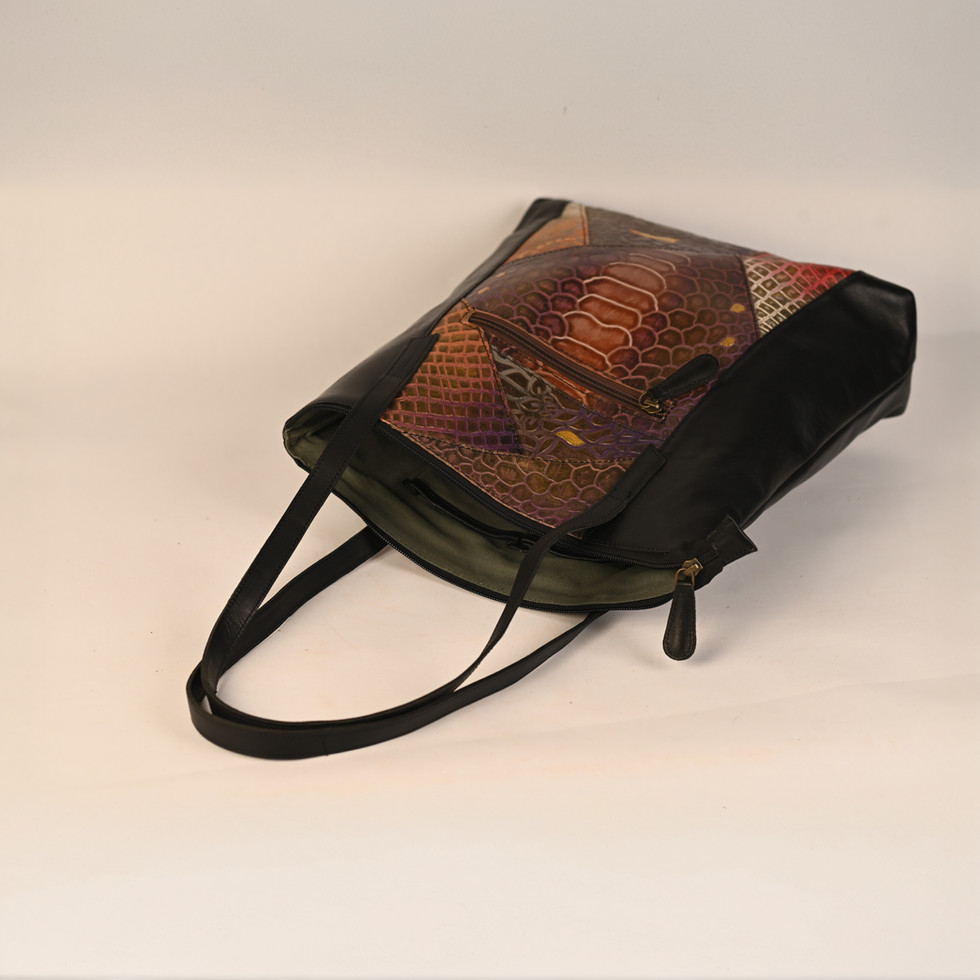 Black leather handbag with patterned fabric inside on white background