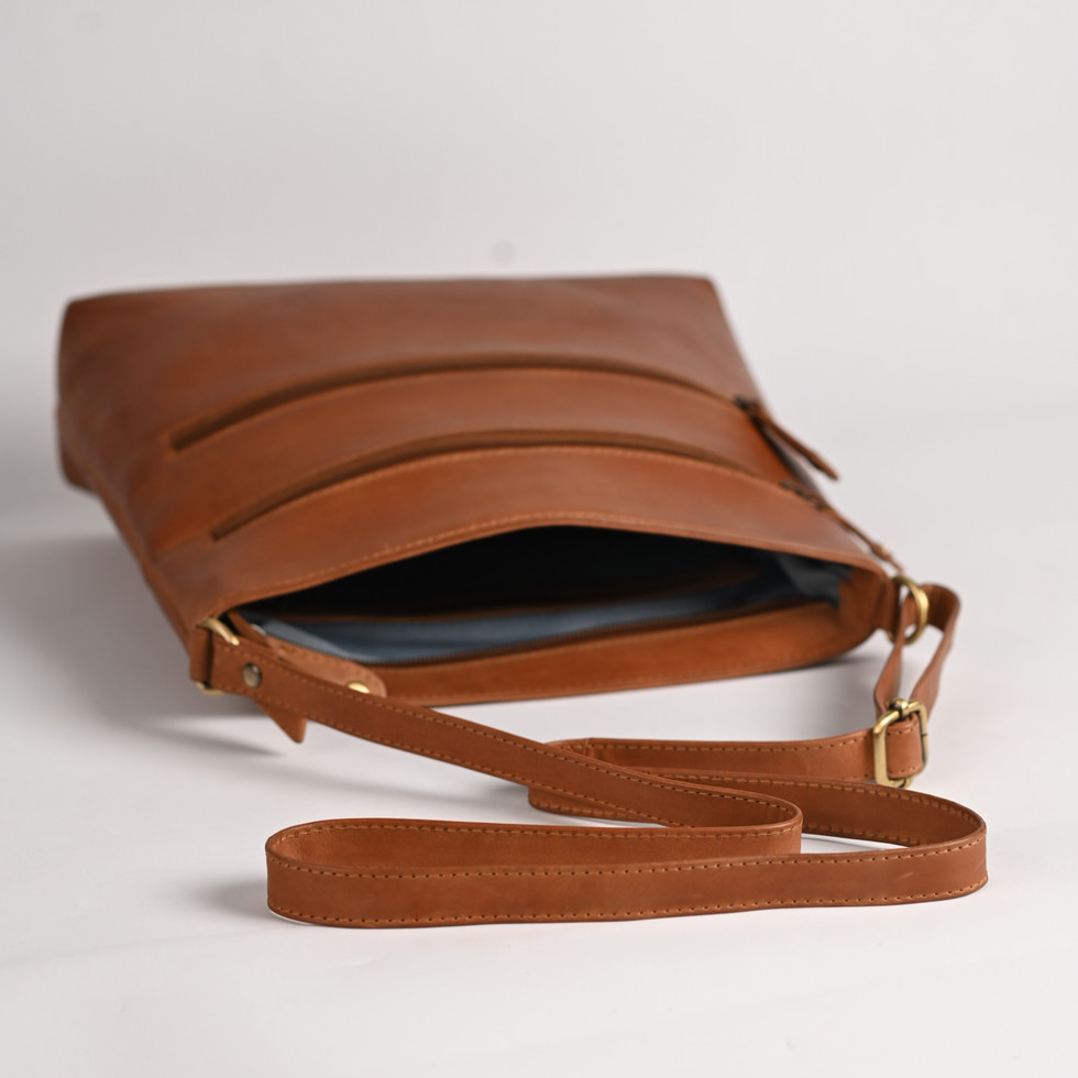 Brown leather crossbody bag with three zippers and adjustable strap