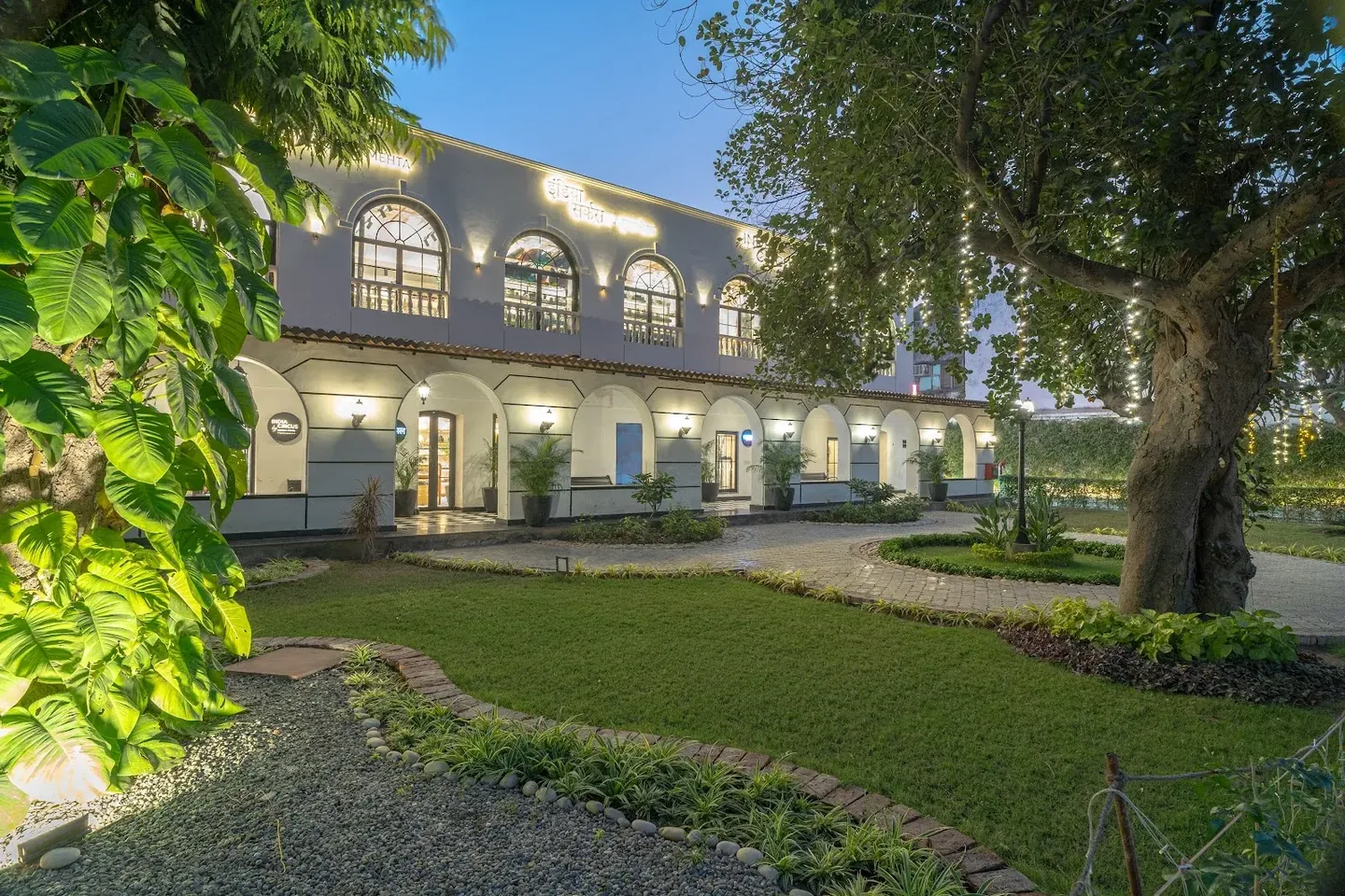 The Le Press gardens and illuminated heritage building at dusk