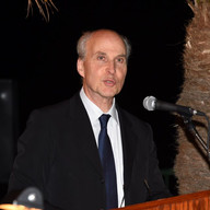 A man speaking on a podium wearing a formal attire.