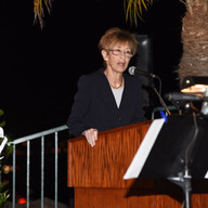 A woman speaking on a podium wearing a formal attire.