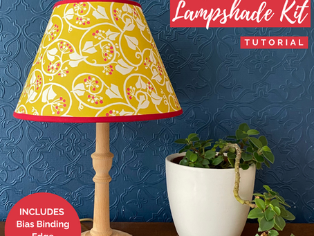 A yellow paper lampshade on a sideboard with a plant 