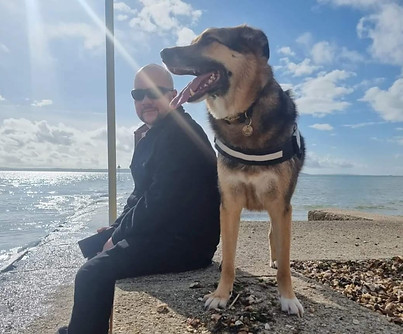 Man sitting on water's edge with dog