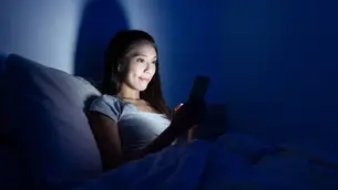 Mujer acostada viendo el celular como un mal hábito