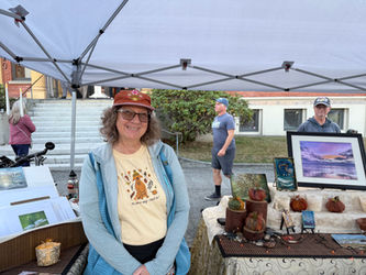woman artist smiling at her booth with her artwork