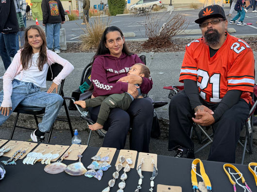 family of four sitting at their booth smiling with handmade jewelry on the table