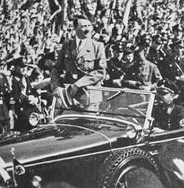1943 photo of Adolf Hitler in a Mercedes — leading a parade of Nazis down the first completed stretch of road between Frankfurt and Darmstadt.