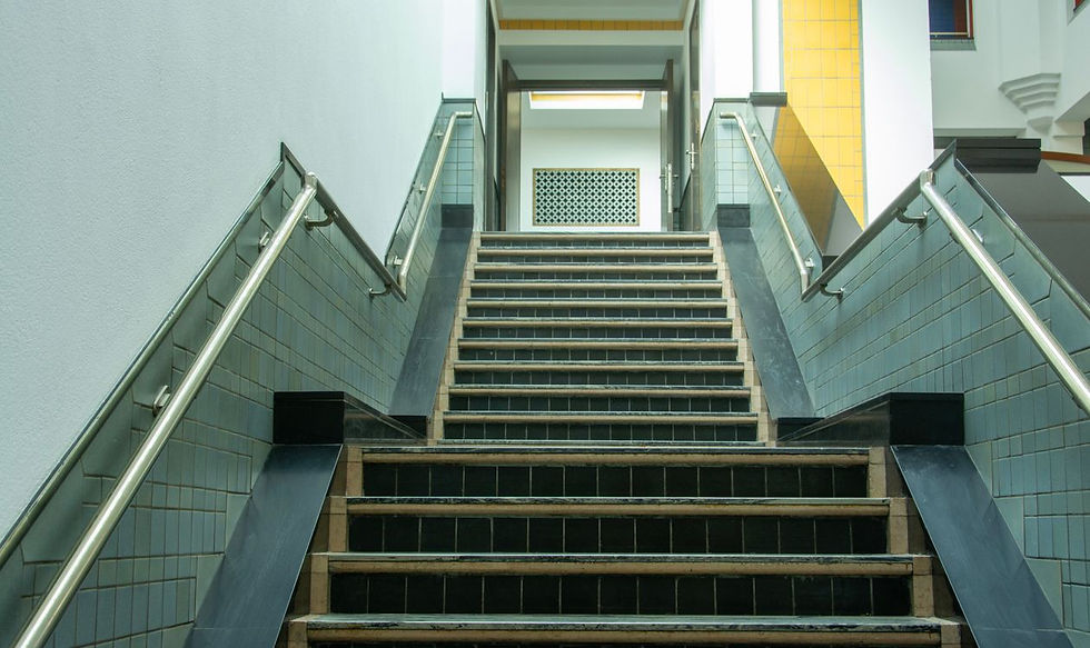 Treppe mit Metallgeländer und gefliesten Stufen in einem Wohngebäude als Beispiel für ein saniertes Treppenhaus