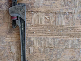 Rohrzange auf einer Holzfläche als Sinnbild für den Handwerker-Notdienst bei einer Havarie in der Immobilie