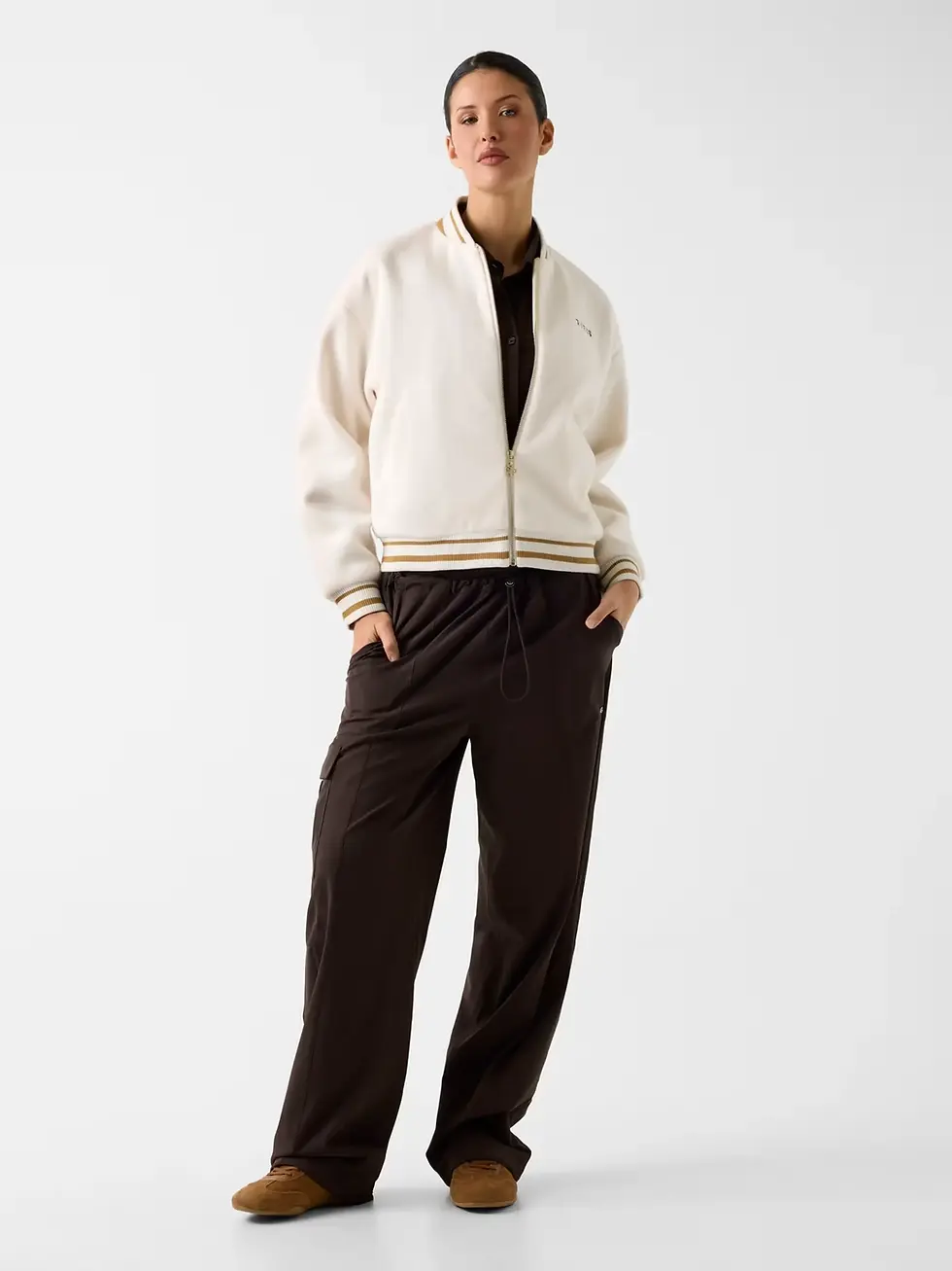 Chaqueta bomber mujer blanca de Guess combinada con pantalón oscuro en un conjunto elegante y moderno