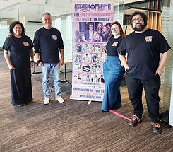 The Caricatures by Marietta team posing next to a sign showing their caricatures at a company event in Overland Park, KS.