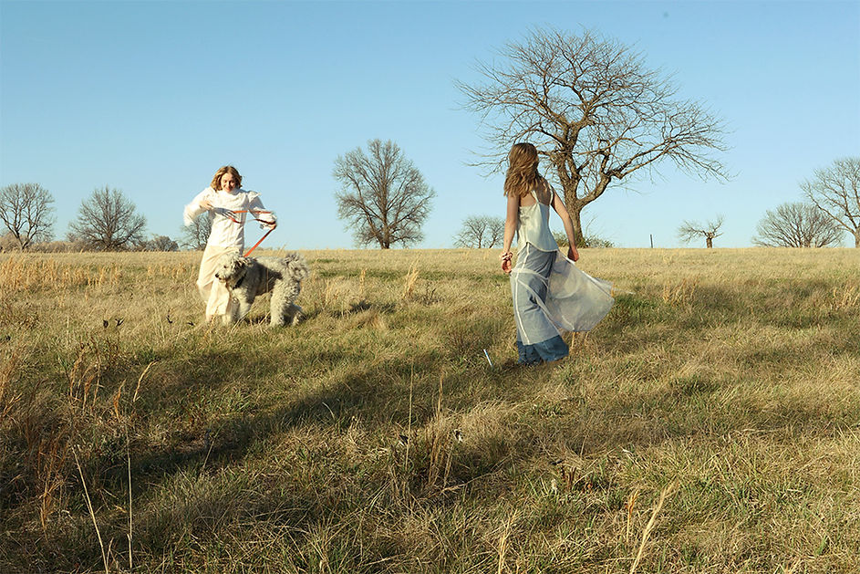 A photograph of two girls standing at opposite ends of a field, moving, gently.